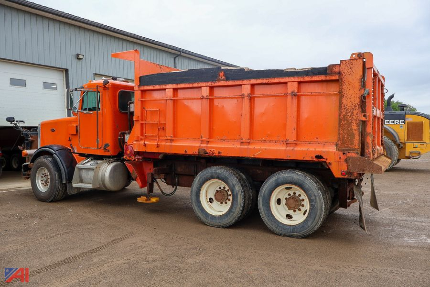 Peterbilt 357 dump truck with orange cab and dump bed, side view.