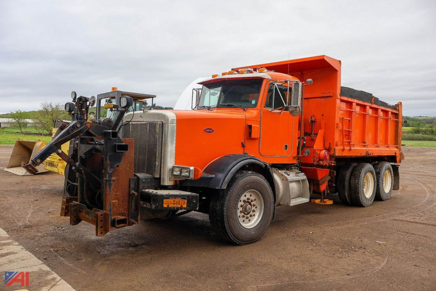 Peterbilt 357 dump truck with plow attachment in orange and white cab, residential front plow and large orange dump bed.