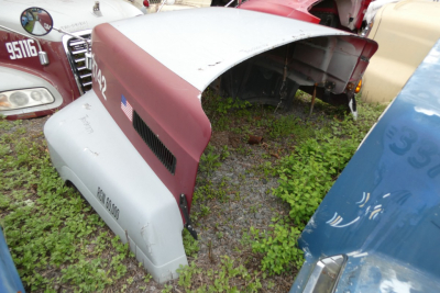 Mack CH612 hood and fender panels with maroon and light gray paint, exterior components on grass, truck parts yard.
