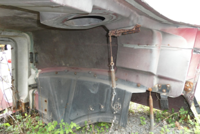 Underbody of a Mack CH612 hood area showing inner panels and hinges with visible rust and a spring mechanism.