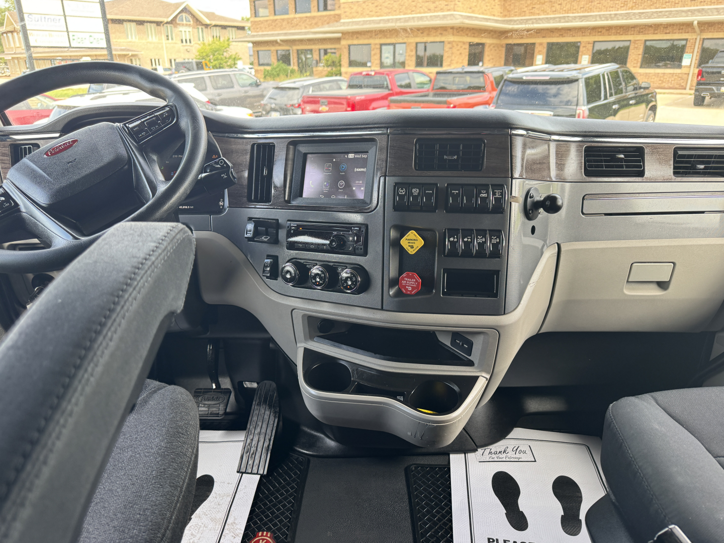 Peterbilt 579 dash and front interior showing steering wheel, center console with touchscreen, climate controls, and storage compartments in a sleeper cab.