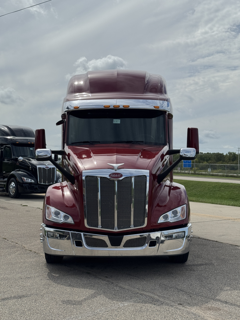 Peterbilt 579 truck front view in burgundy with chrome grille and large bumper.