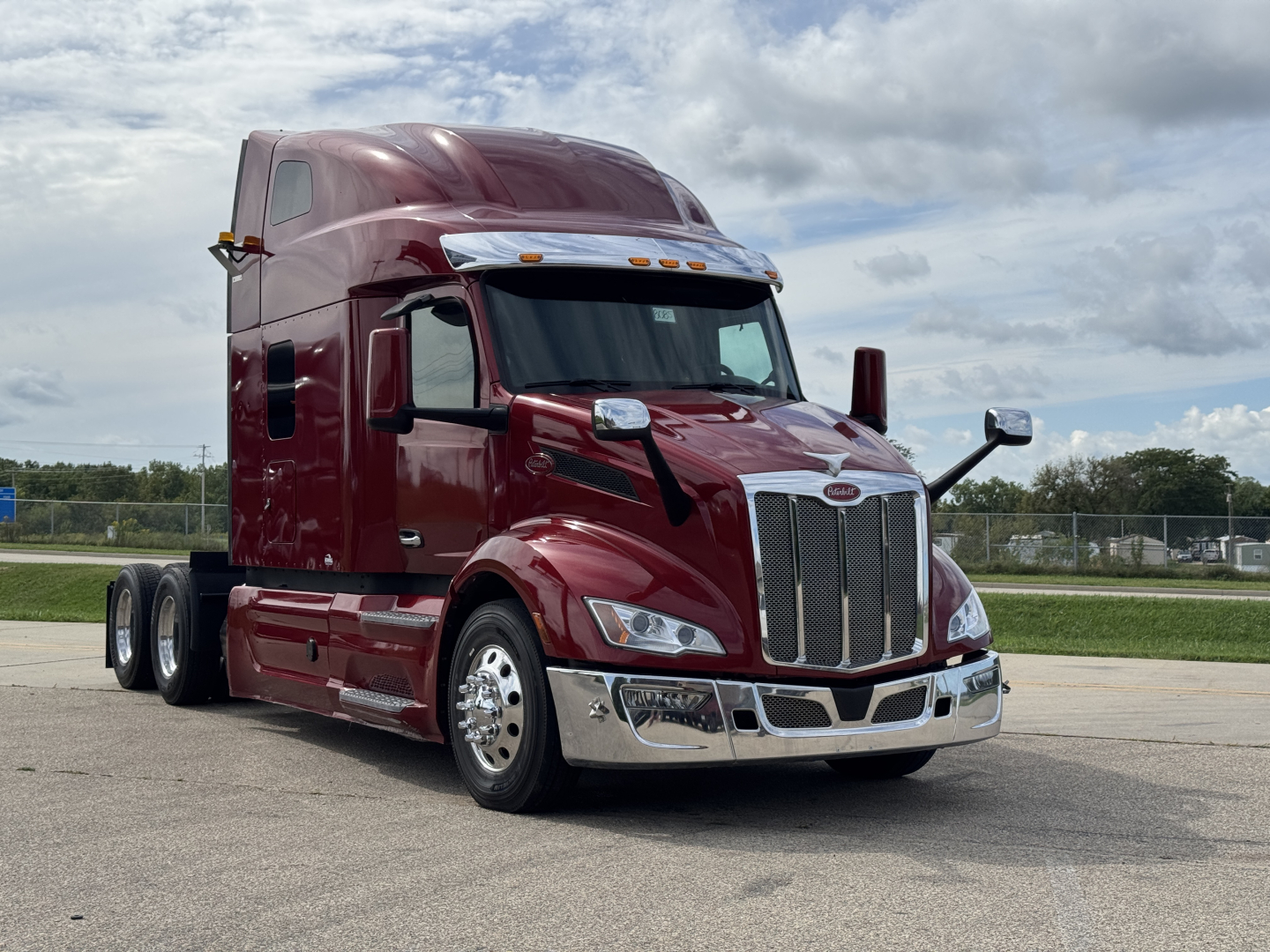 Peterbilt 579 semi-truck, maroon exterior, chrome grille, dual rear axles, daytime running lights, large aerodynamic mirrors.