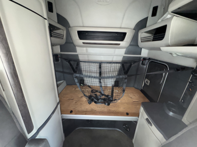 Peterbilt 579 cabin interior view showing sleeper area with wooden platform, cargo net, and storage compartments.