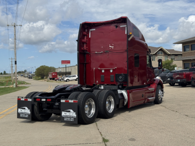 Peterbilt 579 conventional sleeper truck rear three-quarter view showing dual rear axles and red cab with APU area.