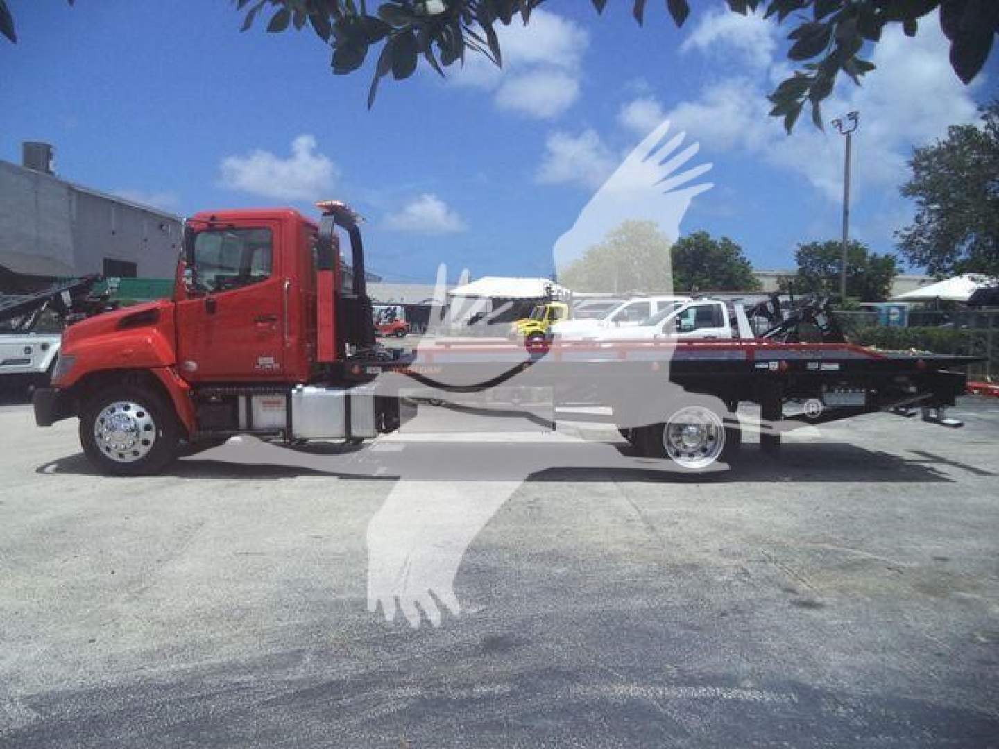 2020 Hino 268A rollback truck side view with red cab and flatbed, stock number tag overlaid watermark; no legible model text visible