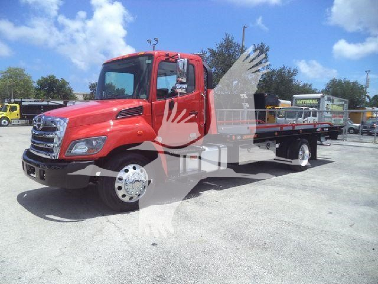 Truck bed rollback tow truck with red cab and wheel-lift from side view showing cab, front grille, and flatbed.