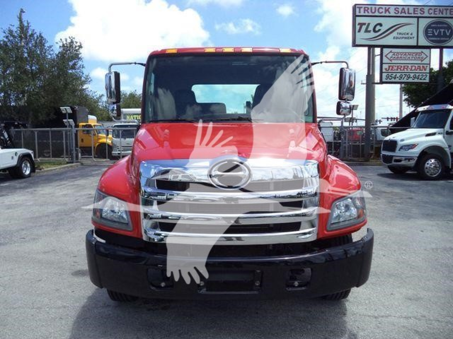 Front view of a red 2020 Hino 268A rollback truck with chrome grille and large bumper, dealership lot in background.