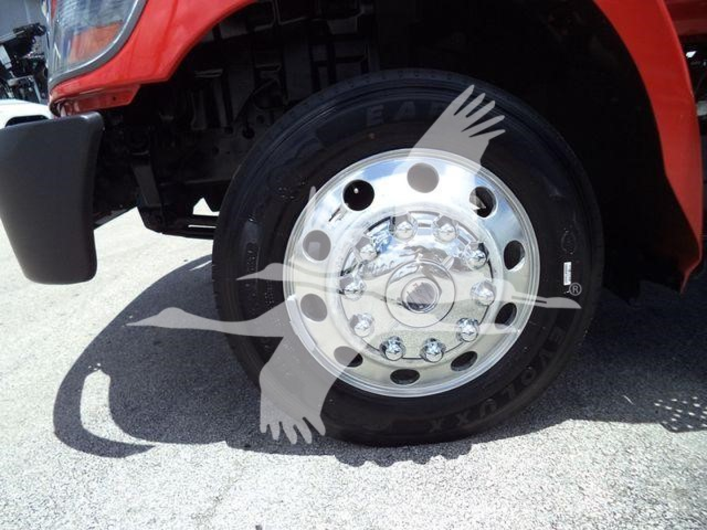 Front wheel of a red 2020 Hino 268A roll-back truck showing a polished steel wheel with multiple lug nuts and tire.