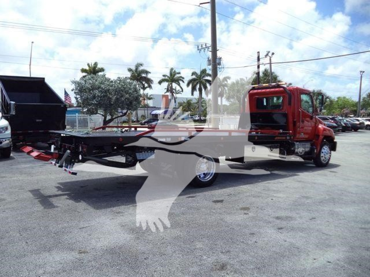 Hino 268A rollback tow truck with a red cab and extended flatbed, side view showing crane and ramps.
