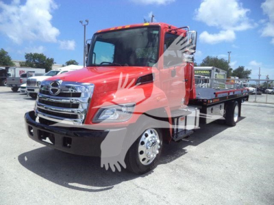 Truck side view showing red 2020 Hino 268A rollback tow truck with flatbed, chrome grille, and dual rear axles.