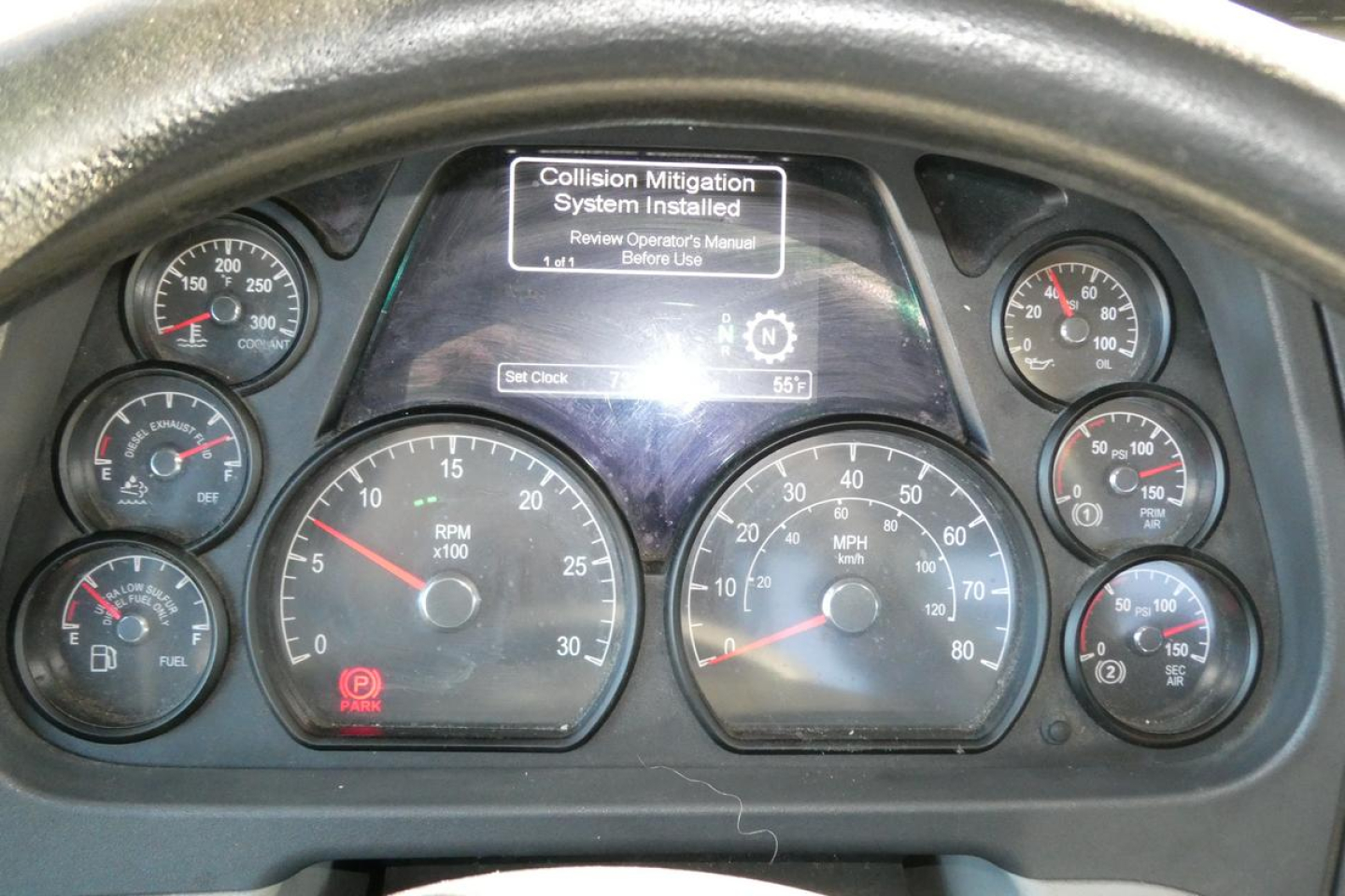 Dashboard cluster of a Peterbilt 579 showing multiple analog gauges and a central display with ‘Collision Mitigation System Installed’ message.
