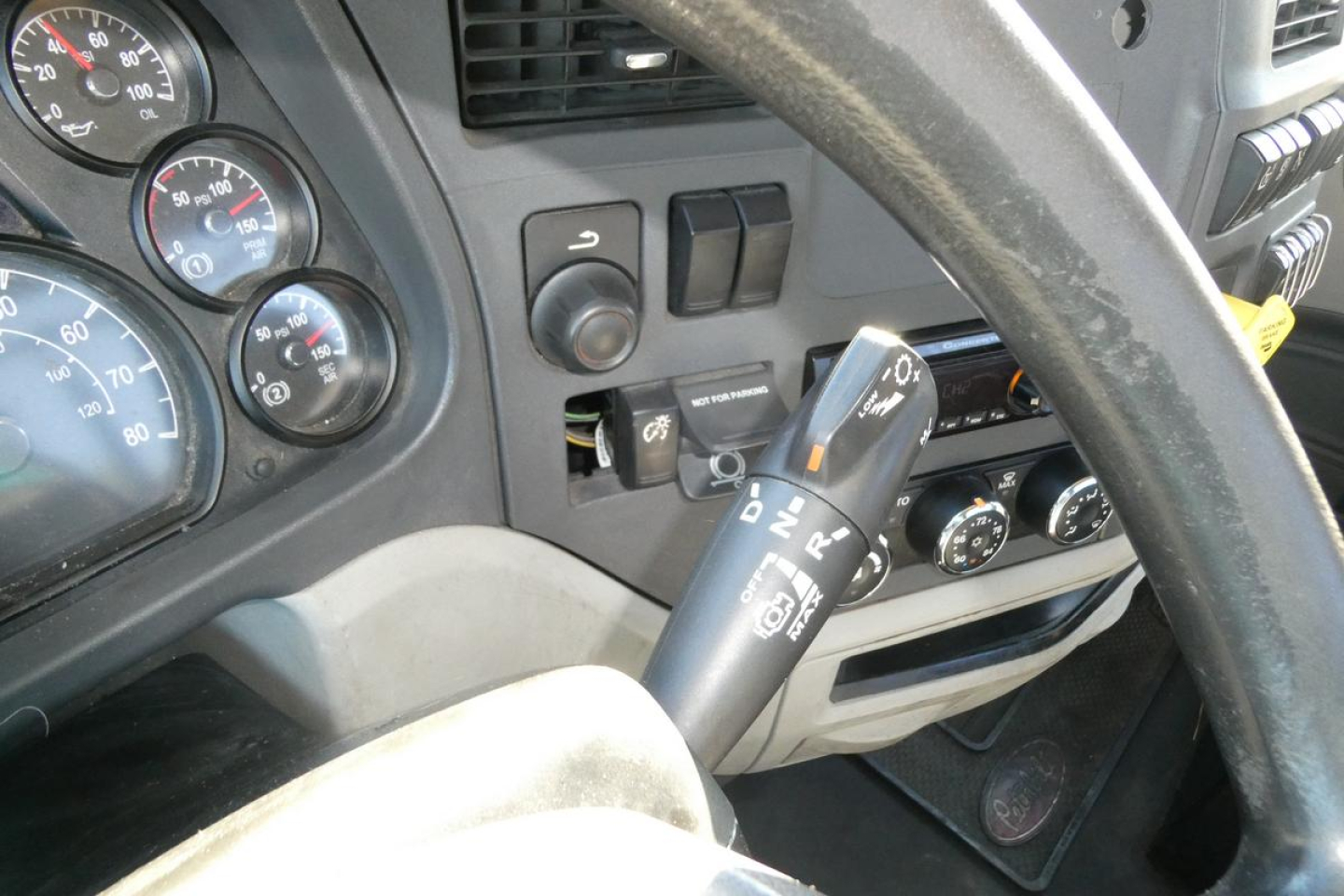 Peterbilt 579 dashboard and steering column view showing tilt/telescoping lever and stalks with gauges visible.