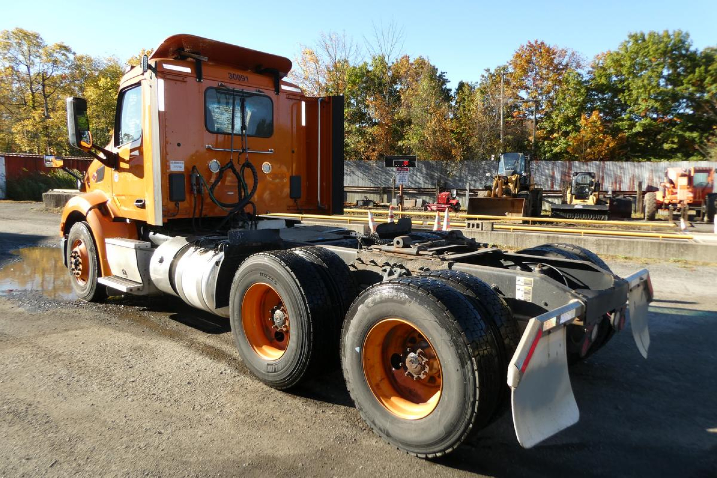 Peterbilt 579 daycab chassis in orange with triple rear axles and flatbed frame
