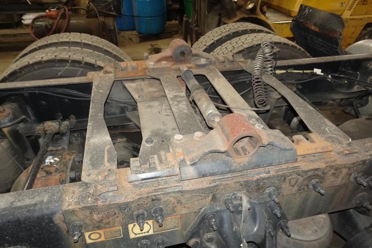 Tractor-trailer chassis view undercarriage showing fifth wheel and frame rails with visible suspension components.