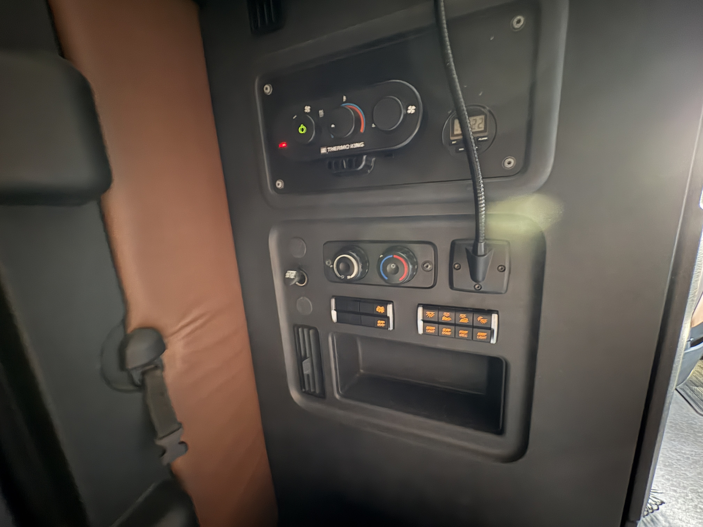 Cabin control panel and dashboard view inside a 2022 Freightliner Cascadia 126 showing controls, knobs, and a power outlet with a mic.