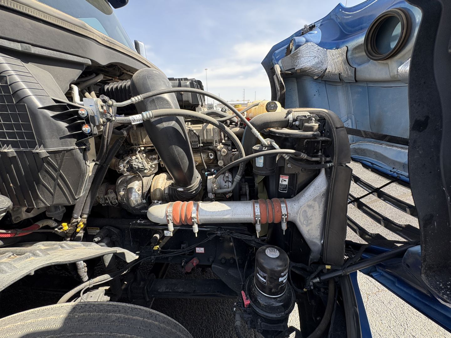 Diesel truck engine bay of a 2022 Freightliner Cascadia 126 showing radiator components, hoses, air intake, and various engine fittings.
