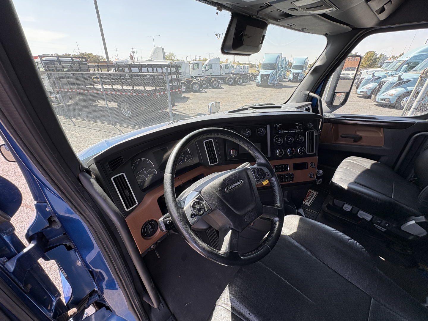 Cab interior of a Freightliner Cascadia 126 truck showing steering wheel, dashboard, and front seat area.