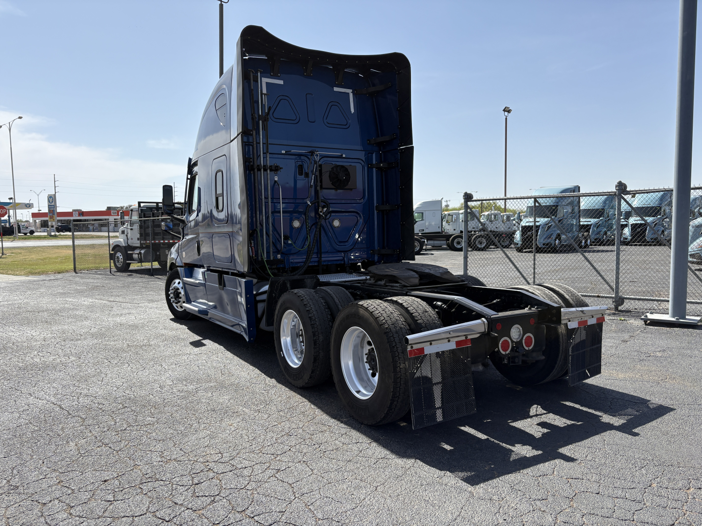 Freightliner Cascadia 126 tractor in blue, rear view showing fifth wheel and dual rear axles in a used trucks lot.