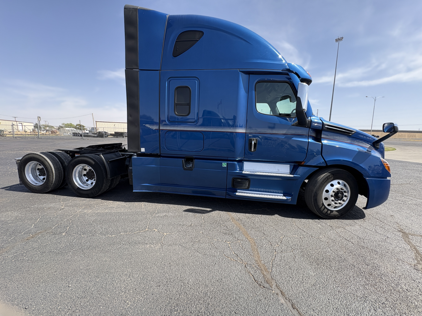 Freightliner Cascadia 126 sleeper cab side view showing blue truck with black aero fairing and dual rear axles.