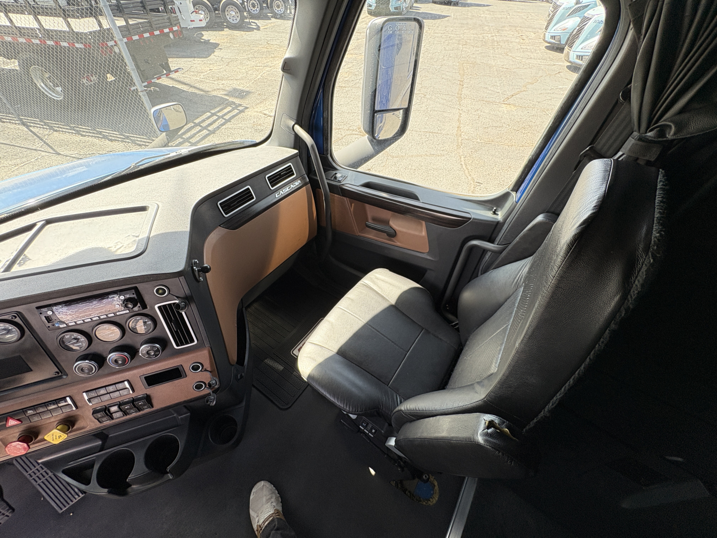 Freightliner Cascadia 126 interior front cab showing dashboard, steering wheel, and driver's seat with beige/black trim.