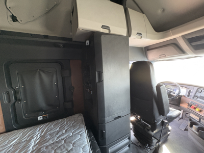 Cab interior of freightliner cascadia 126 showing captain seat and overhead cabinets with a tall central cabinet unit.
