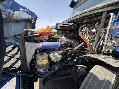 Freightliner Cascadia 126 engine bay with exposed components including hoses, wiring harness, coolant reservoir, and air intake visible.
