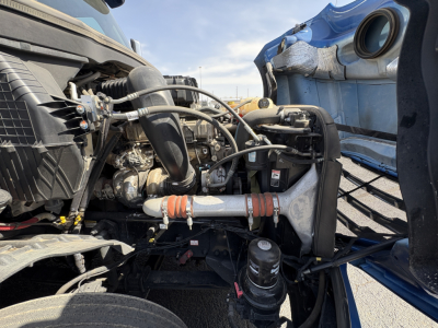 Diesel truck engine bay of a 2022 Freightliner Cascadia 126 showing radiator components, hoses, air intake, and various engine fittings.