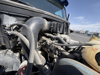 Truck engine bay of a 2022 Freightliner Cascadia 126 showing hoses, coolant reservoir, and engine components.