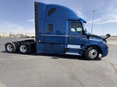 Freightliner Cascadia 126 sleeper cab side view showing blue truck with black aero fairing and dual rear axles.