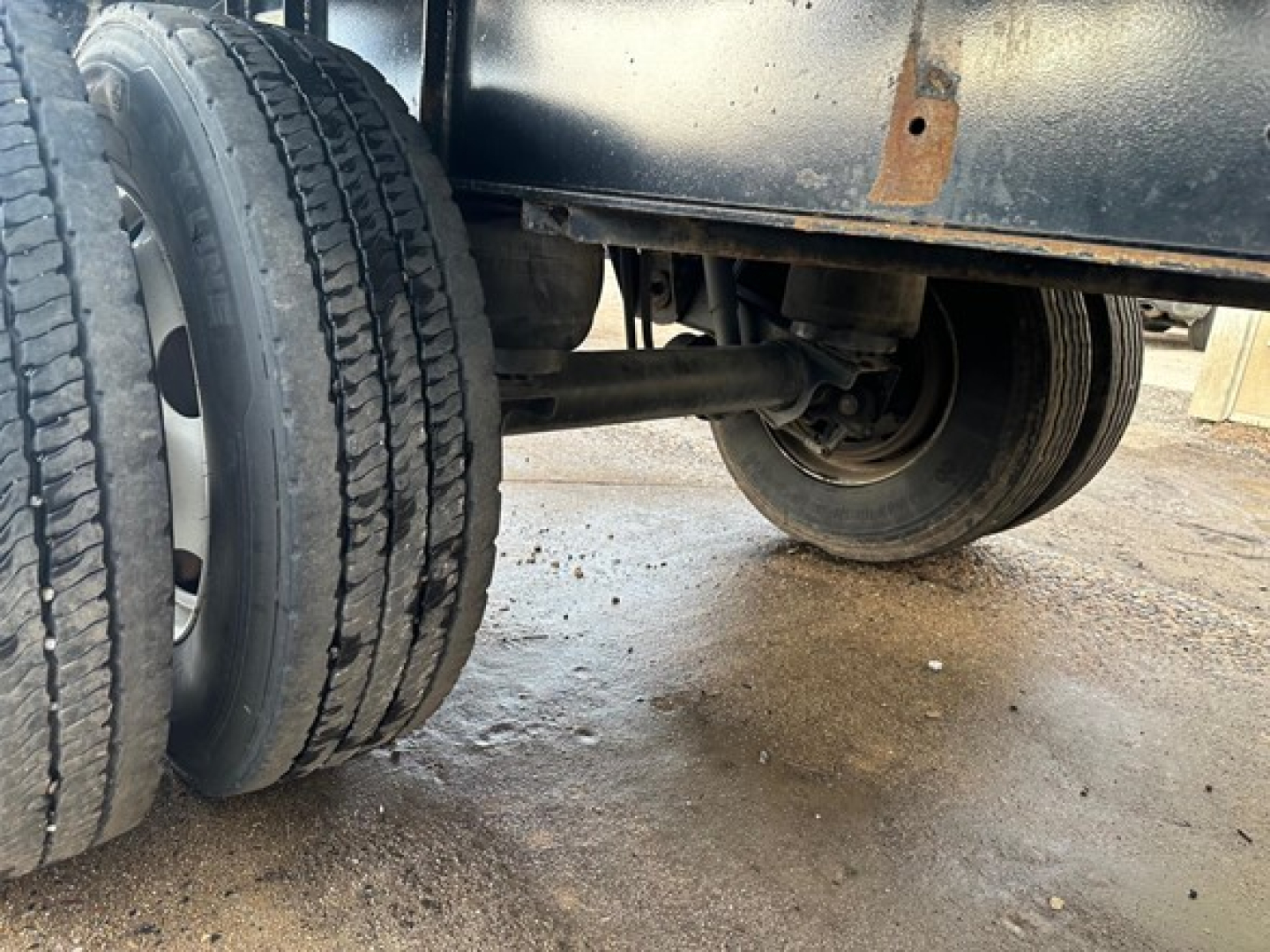 Flatbed trailer undercarriage showing dual rear wheels and suspension components in a listed used Transcraft combo flatbed.
