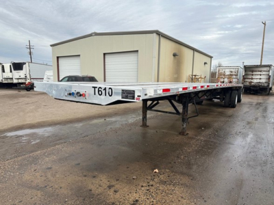 Transcraft combo flatbed trailer in yard showing flatbed deck with undercarriage and front landing gear; model label T610 visible.