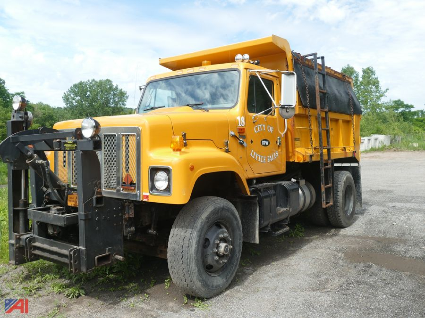 Dump truck with sander body showing front grille, headlights, and yellow paint.