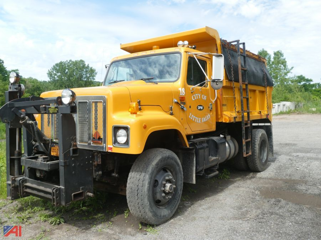 Dump truck with sander body showing front grille, headlights, and yellow paint.
