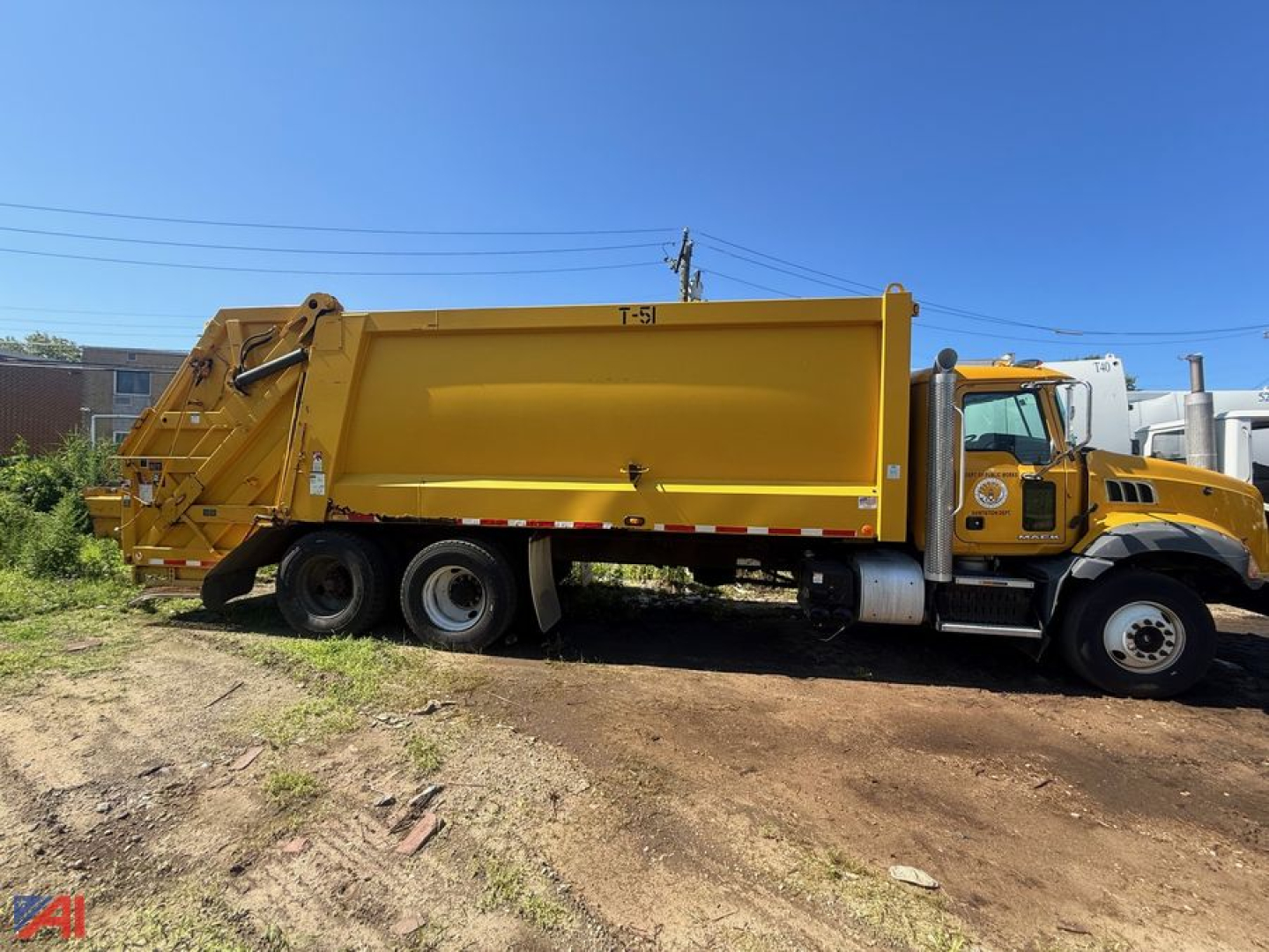 2014 Mack garbage truck side view showing large yellow refuse body and hopper with black tires
