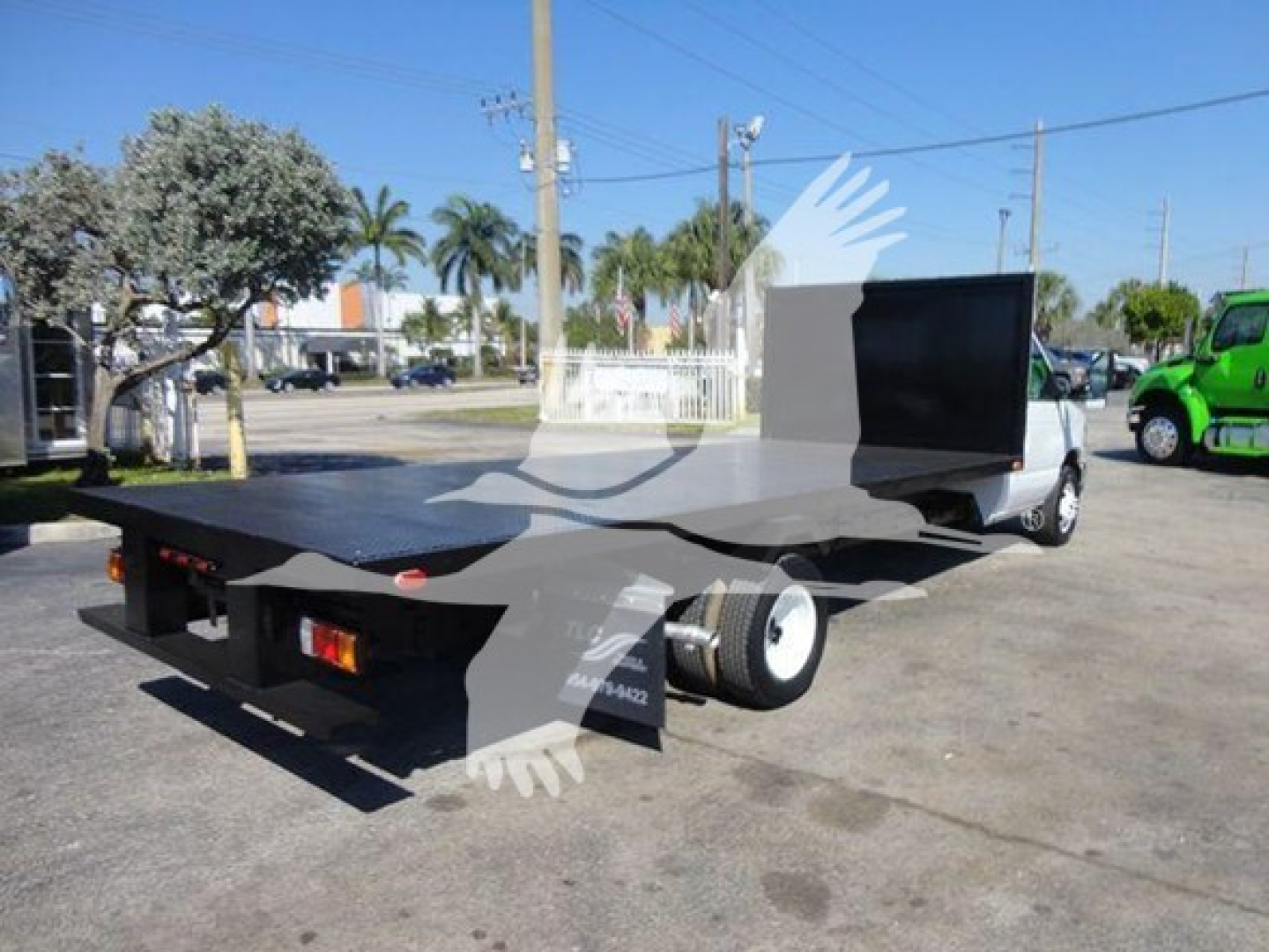 Flatbed tow truck bed and cab of a 2011 Ford E450 with a black flatbed and a tall black utility box in rear, VIN 1FDXE4FS3BDB20639