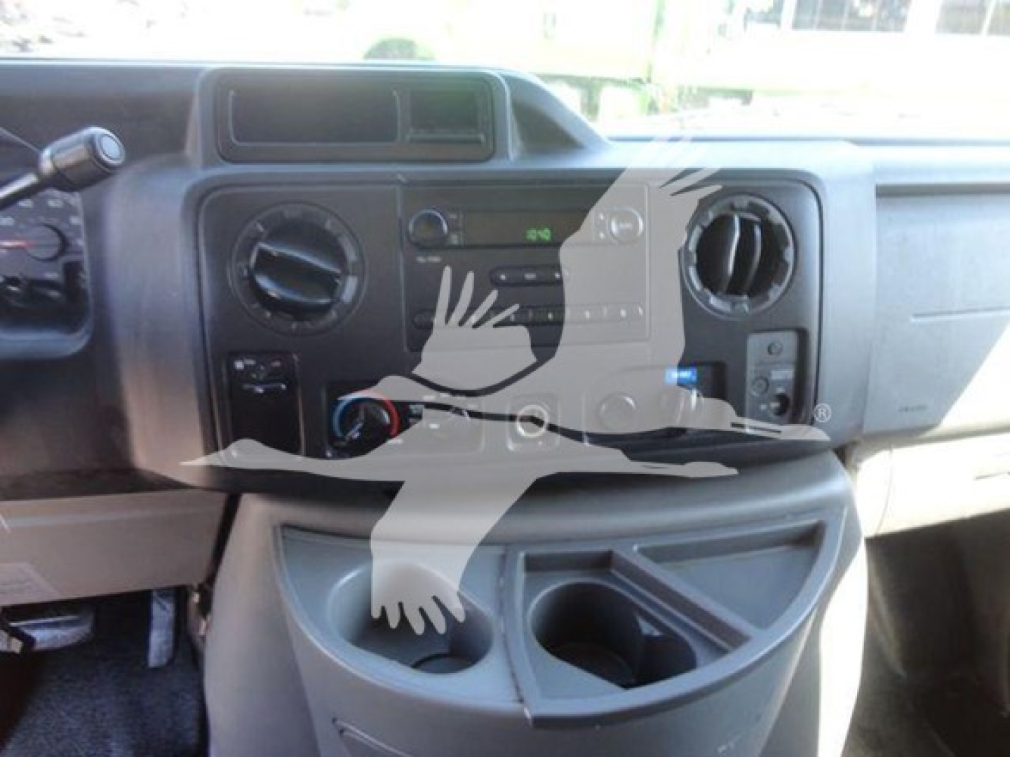 Dashboard and center console of a 2011 Ford E450 cargo/flatbed truck showing air vents, radio, climate controls, cup holders, and storage compartments.
