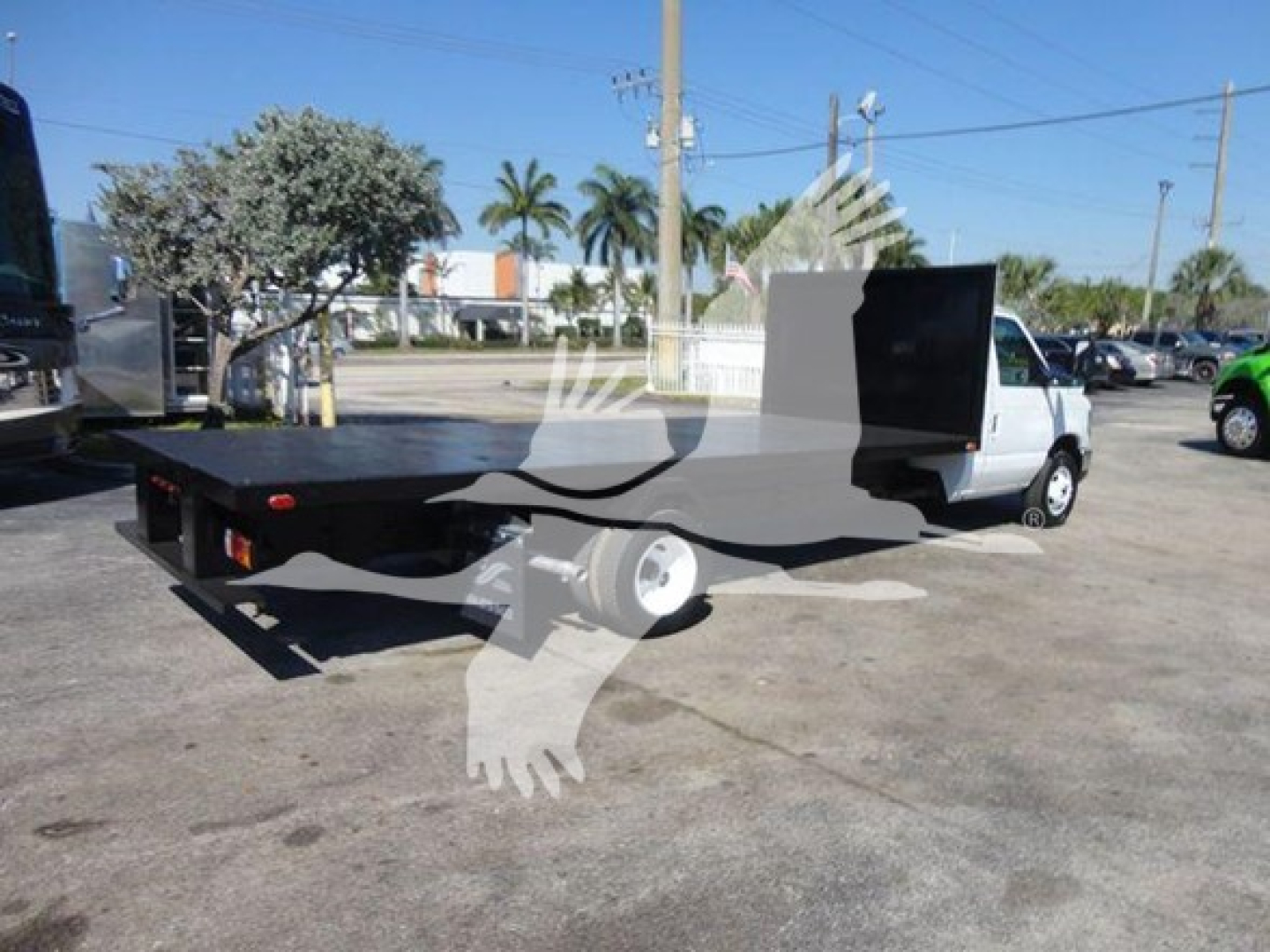 Flatbed tow truck with white cab and black flatbed, side view showing loading area and rear wheels.