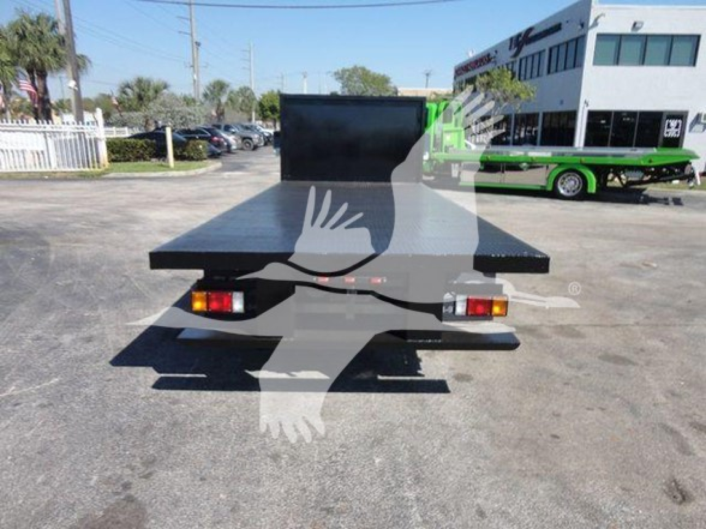 Flatbed tow truck bed on rear of a 2011 Ford E450 with tail lights and spare platform visible.