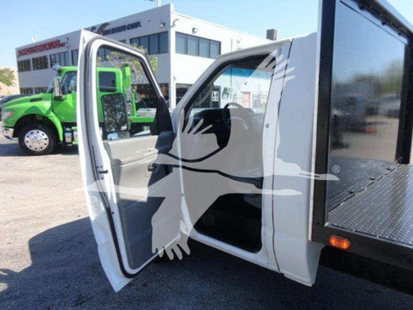 Ford E450 flatbed truck showing open driver door and interior with a black mounted toolbox on the flatbed.