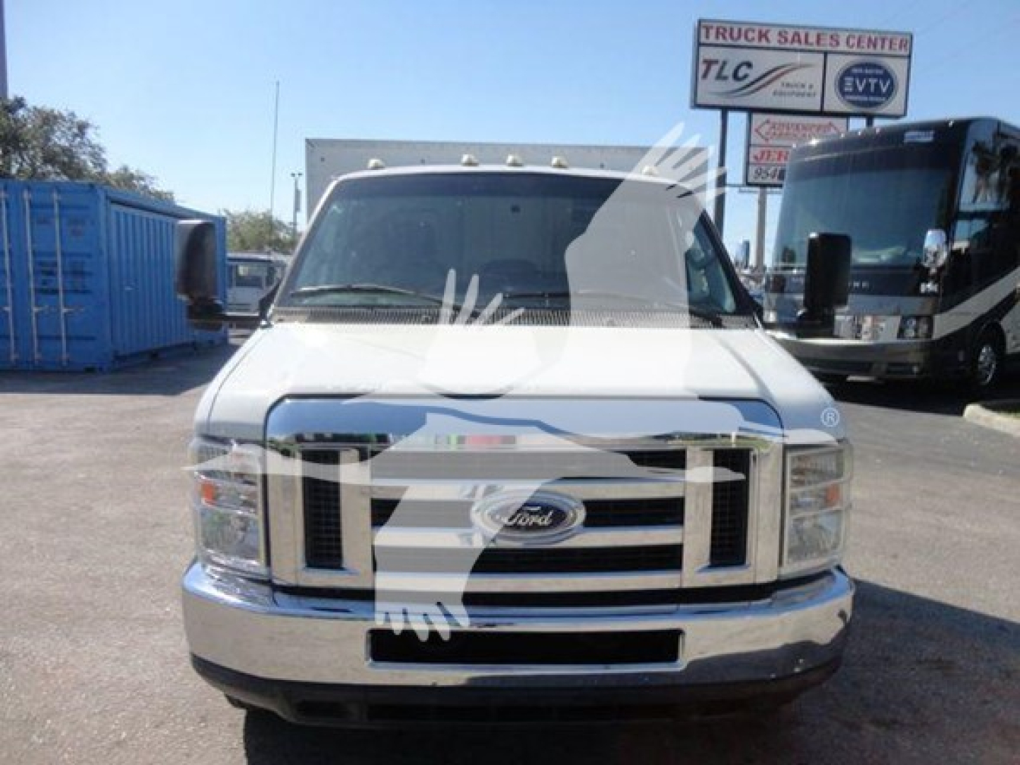 Ford E-Series cutaway/flatbed truck front view showing grille, headlights, Ford emblem, and chrome bumper in a dealership lot.