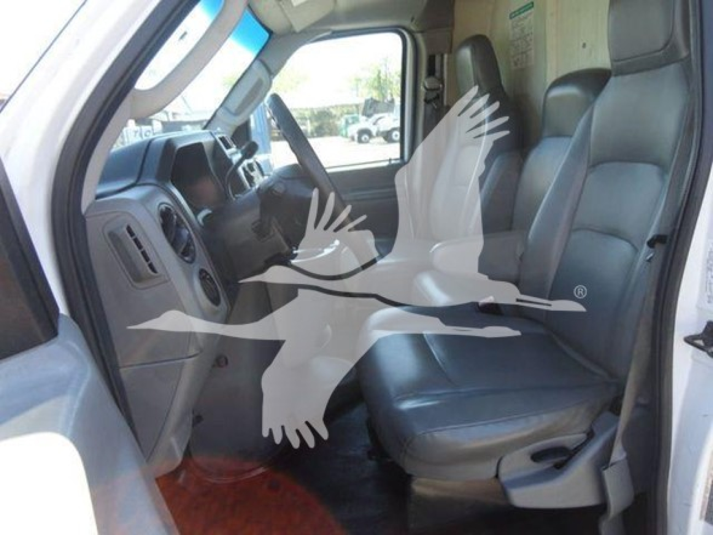 Ford E-450 interior cab view showing front seats and dashboard from open driver's side door.