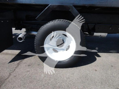 Truck wheel and undercarriage of a 2011 Ford E450 flatbed side view showing rear wheel and exhaust.