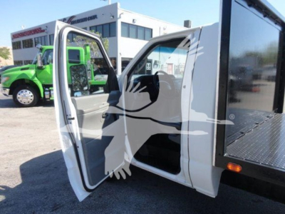 Ford E450 flatbed truck showing open driver door and interior with a black mounted toolbox on the flatbed.