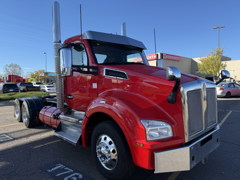 Kenworth T880Class 8 daycab tractor in red, front-right side view, chrome exhaust stacks, large grille, dual rear wheels, chrome bumper, side steps.
