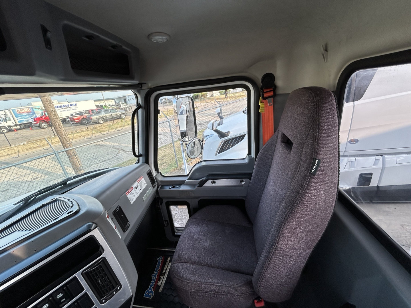 Cab interior of a 2020 Mack GR64B mixer truck showing gray dashboard, steering area, and fabric seat with window and door frame visible.