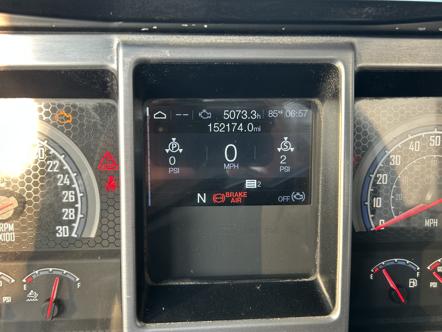 Dashboard center display shows 5073.3h, 85°F, 06:57, odometer 152174.0mi, multiple gauges with N gear indicator, brake air warning, and digital readouts for psi.