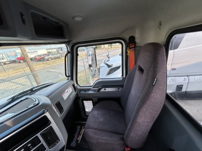Cab interior of a 2020 Mack GR64B mixer truck showing gray dashboard, steering area, and fabric seat with window and door frame visible.