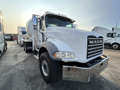 Mack GR64B mixer truck front view showing chrome grille and bumper, white cab, large headlights, and raised mirrors.