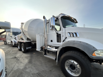 Mixer truck with white cab and cement mixer behind, side view showing the front wheel, chrome exhaust, and stairs.
